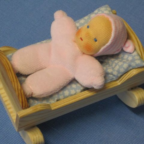 Rosa Minipüppchen in einer kleinen Holzwiege