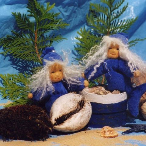 Zwei kleine Meerjungfrauen zwischen Muscheln und Zweigen