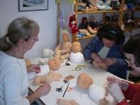Kursteilnehmerinnen am Tisch beim Arbeiten an Puppenköpfen und Puppenkörpern