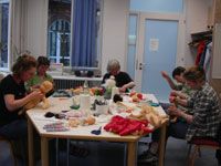 Kursteilnehmerinnen an einem großen Tisch in einem Kursraum beim Arbeiten an ihren Puppen